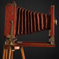 Red bellows camera with tripod. Decorative, not working. Ca. 1905–1925. Antique.