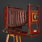 Red bellows camera with tripod. Decorative, not working. Ca. 1905–1925. Antique.